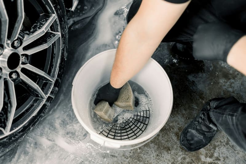 a hand wringing a cloth in a bucket