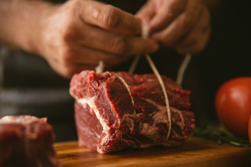 hands tying a joint of beef