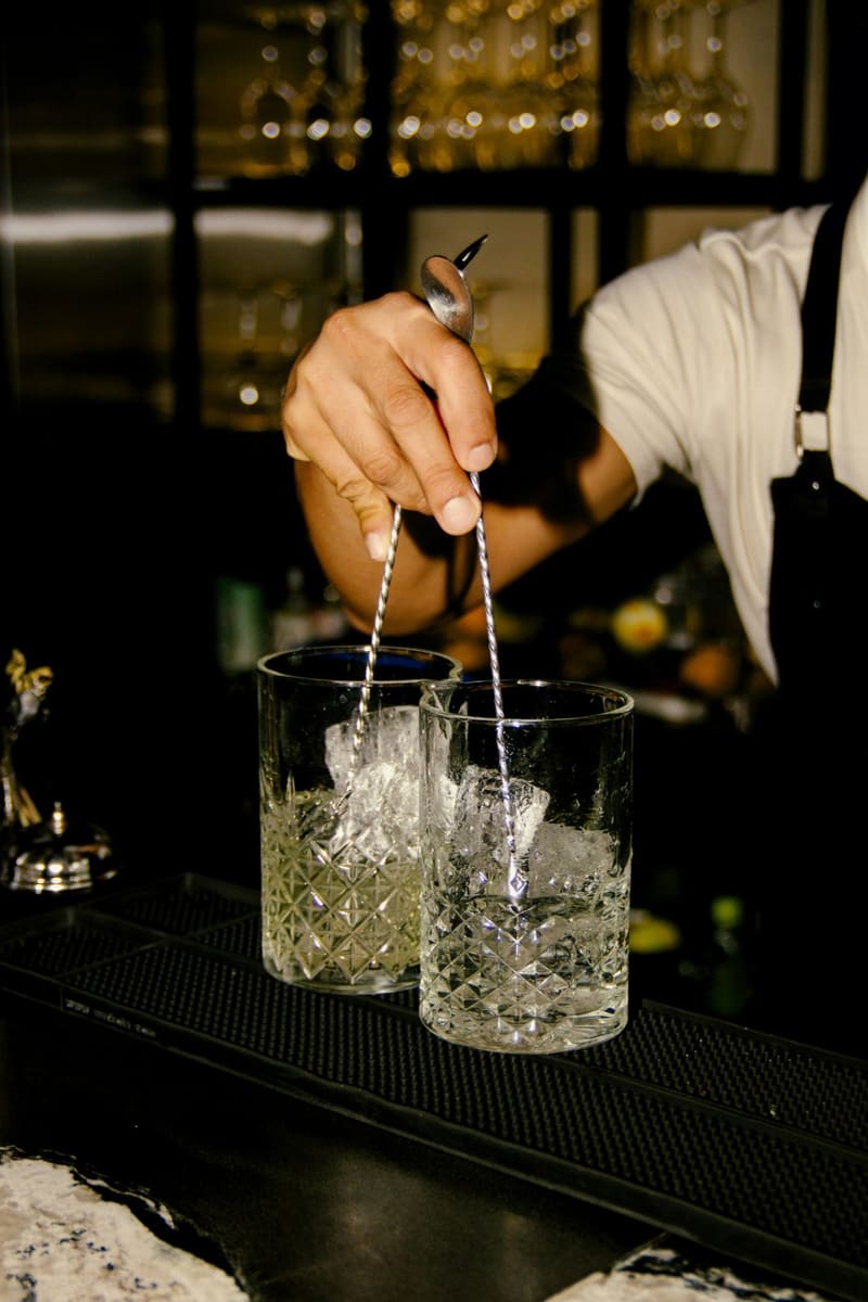 a bartender stirring two mixing glasses