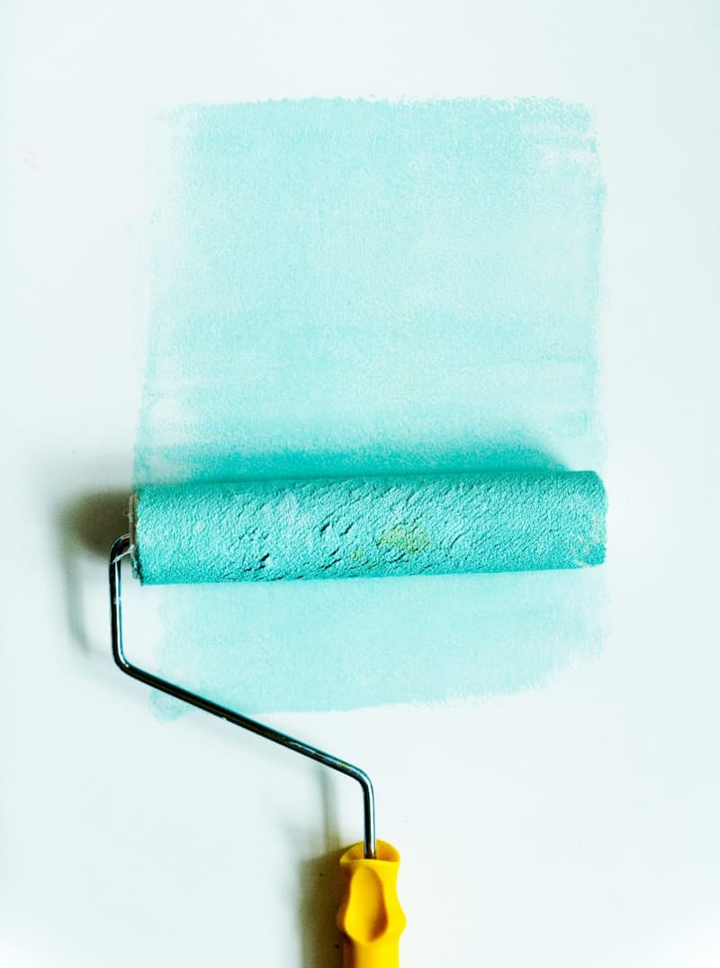 a roller painting turquoise on a wall