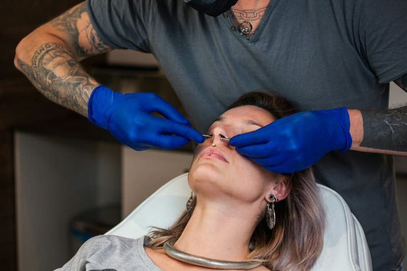 gloved hands doing a facial piercing