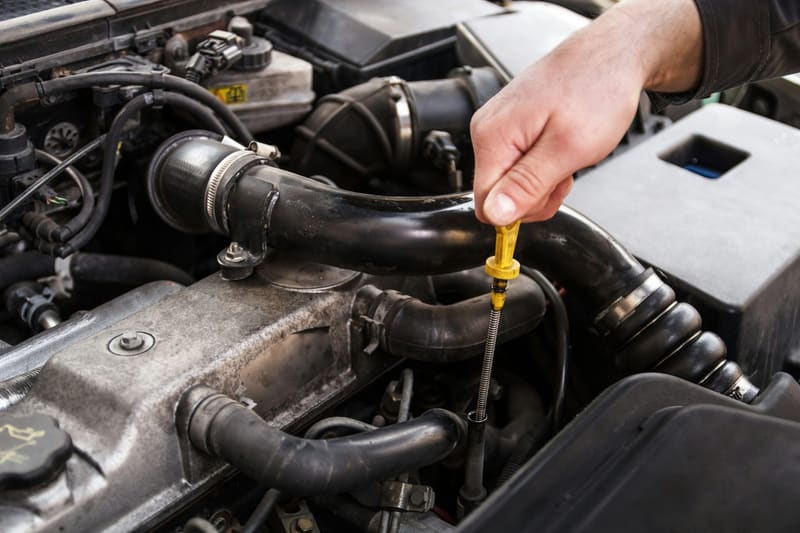 a hand checking an engine dipstick