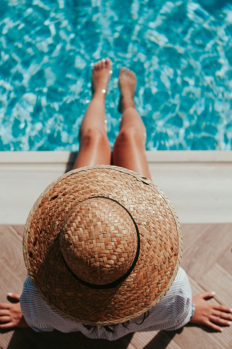 a woman with a straw hat by a pool