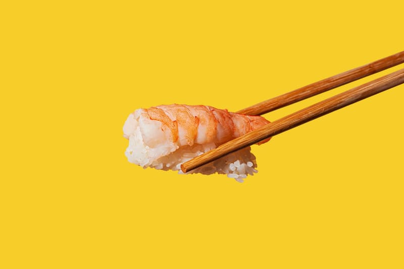 a prawn nigiri in chopsticks