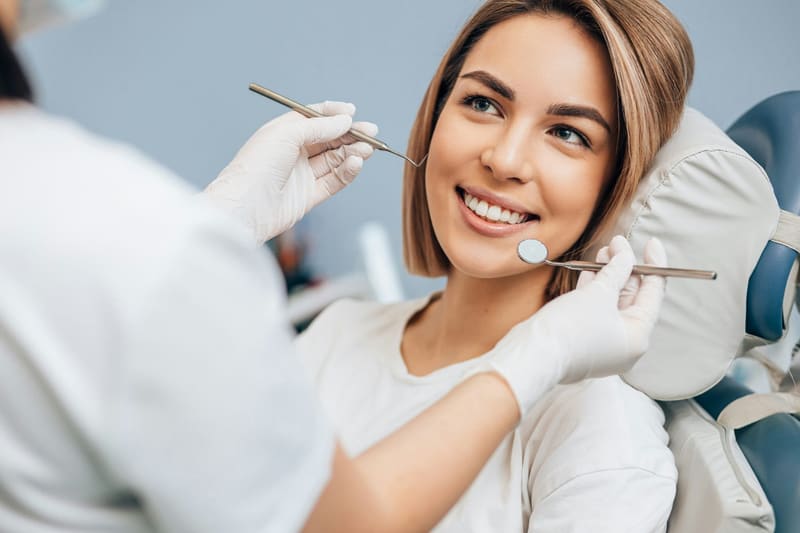 a dentist examining a smiling woman