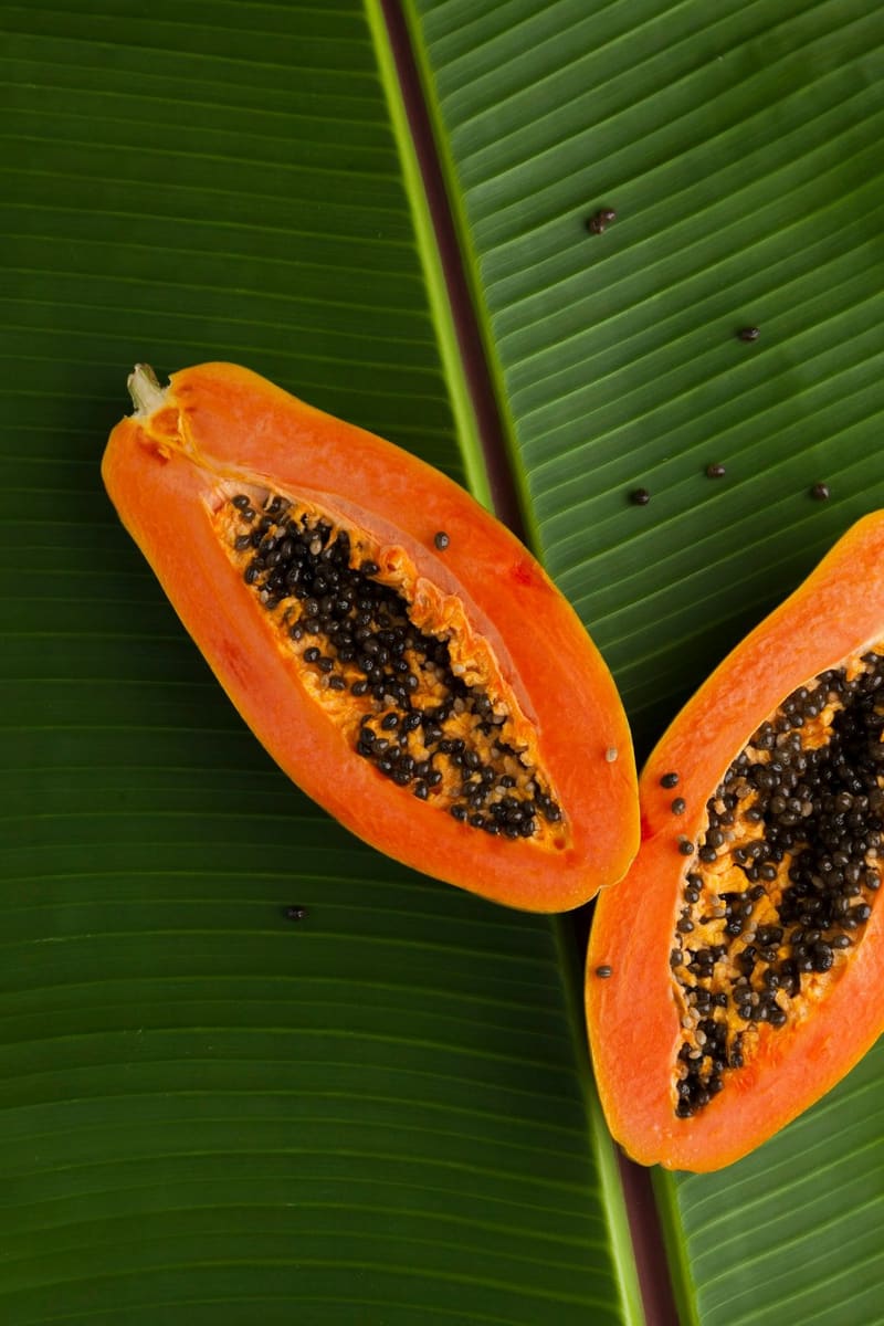 halved papaya on a banana leaf