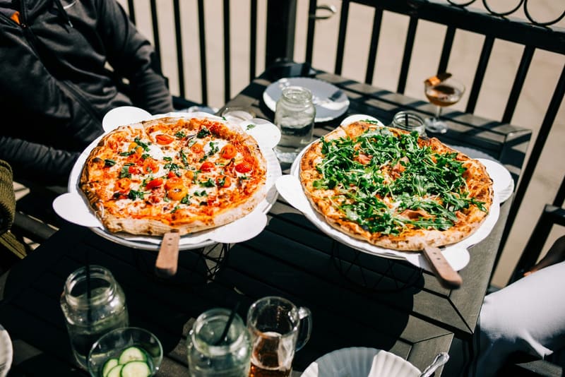 two pizzas on an outdoor table