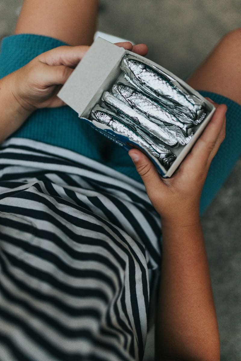 hands holding a tin of sardines