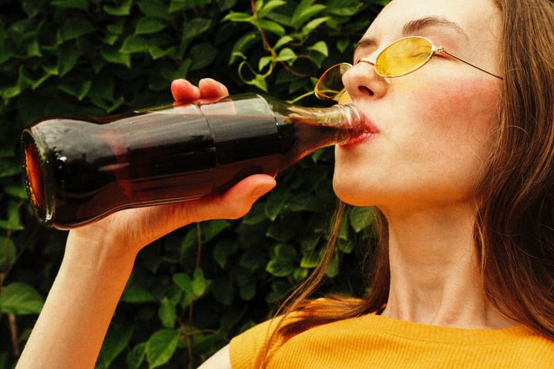 a woman drinking from a cola bottle