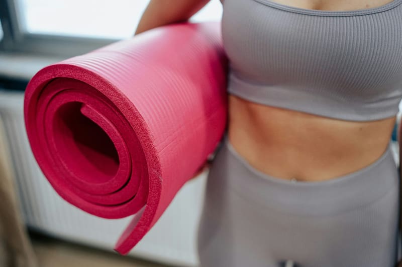 a woman holding a rolled yoga mat