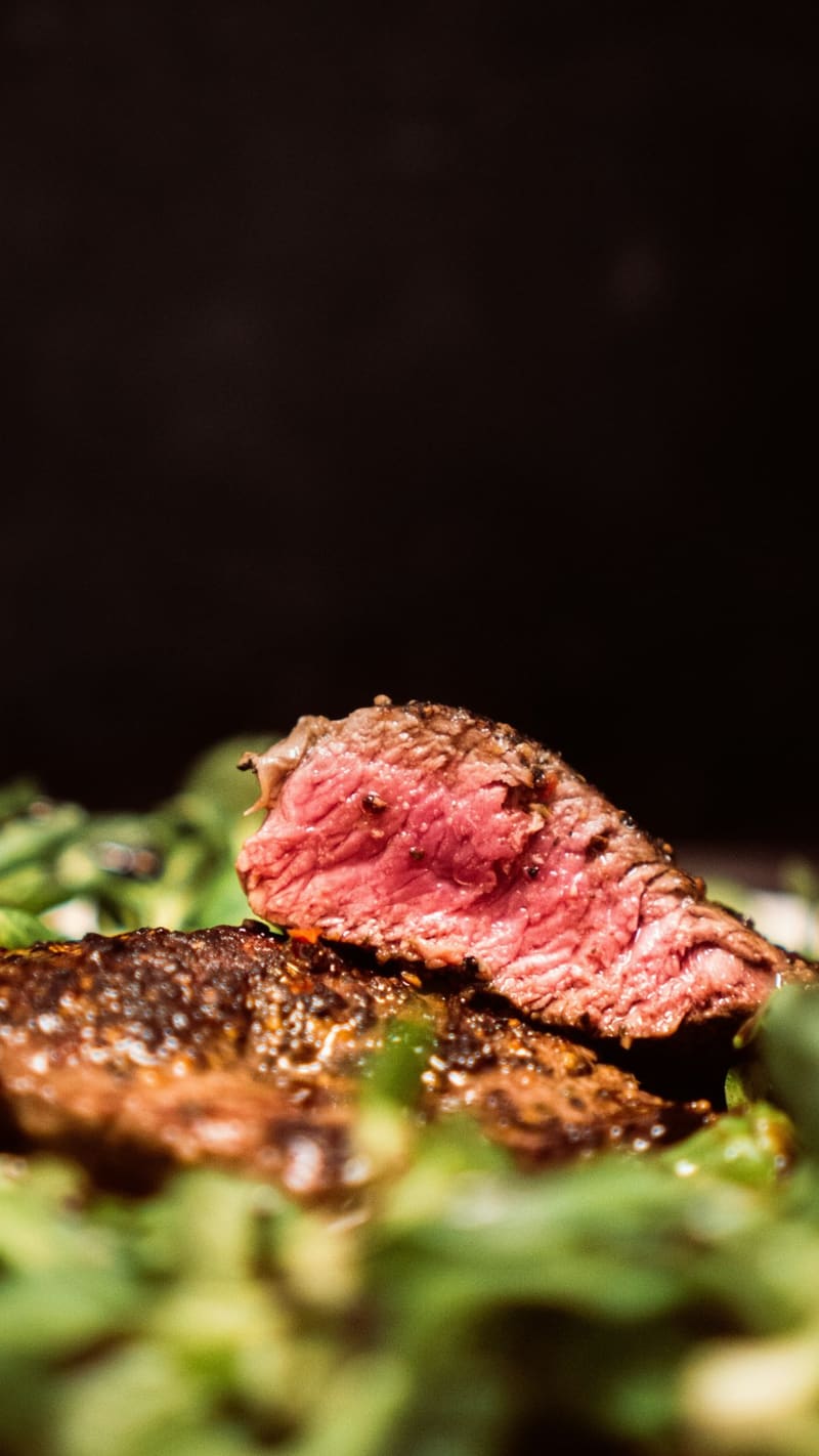 sliced rare steak on greens
