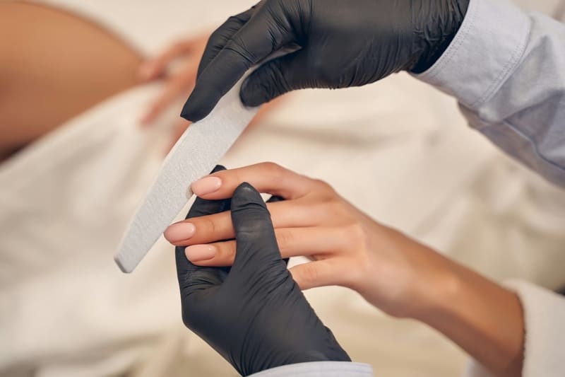 gloved hands filing a nail