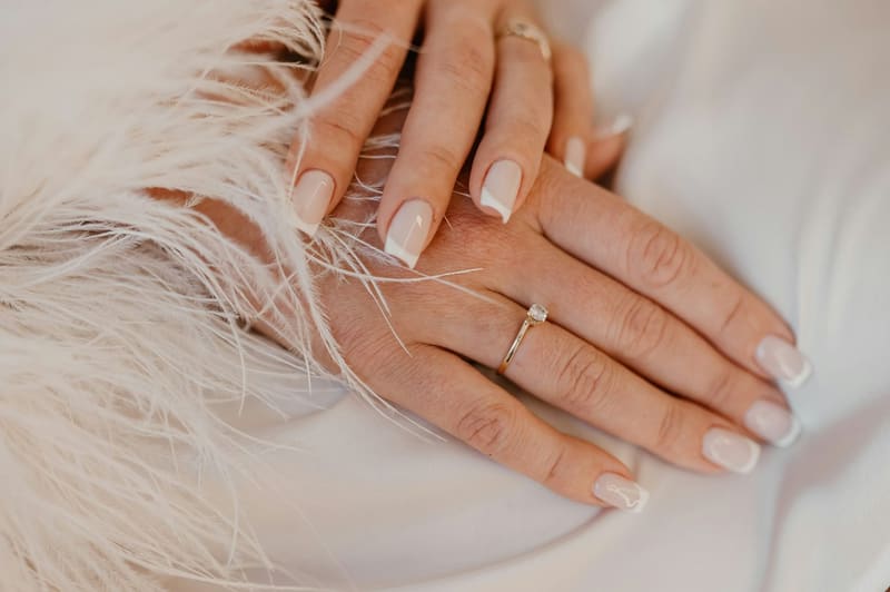 manicured hands on white feathers