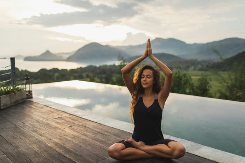 a woman in a yoga pose by a pool