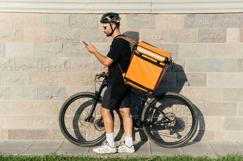 a courier pushing a bike by a wall
