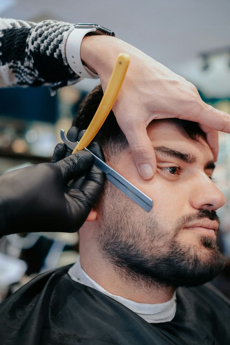 a barber shaving a hairline with a razor