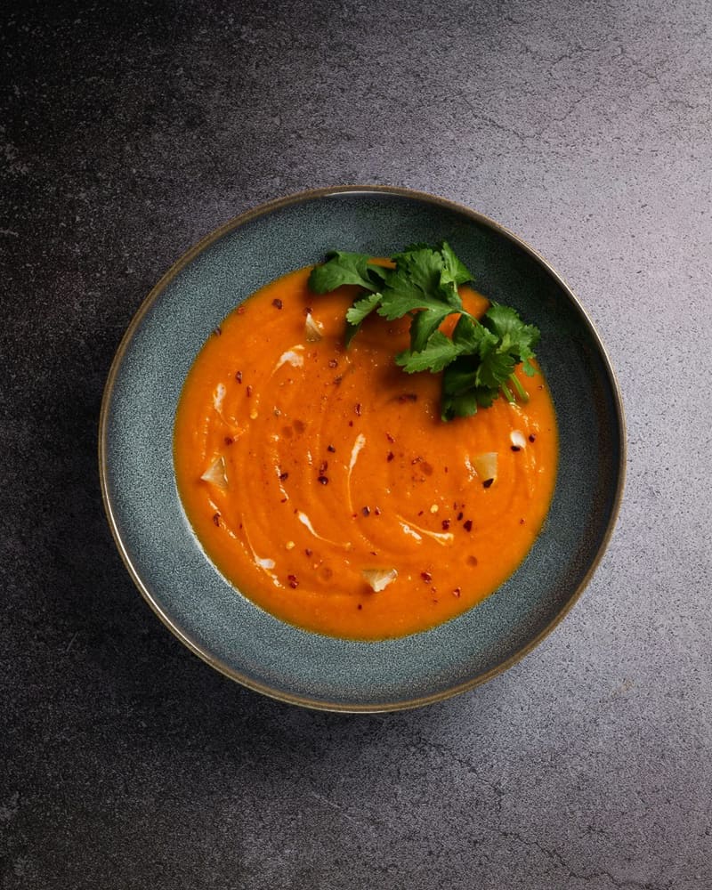 a bowl of orange soup with coriander
