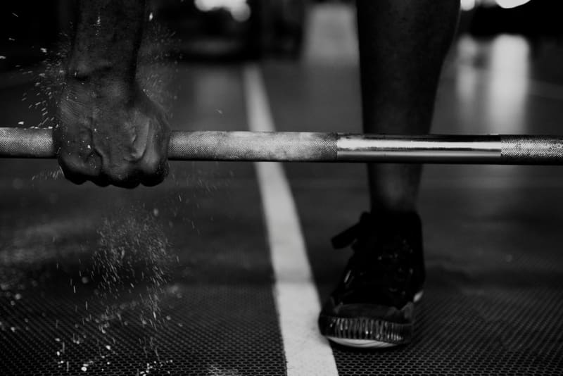 a hand and a barbell with chalk
