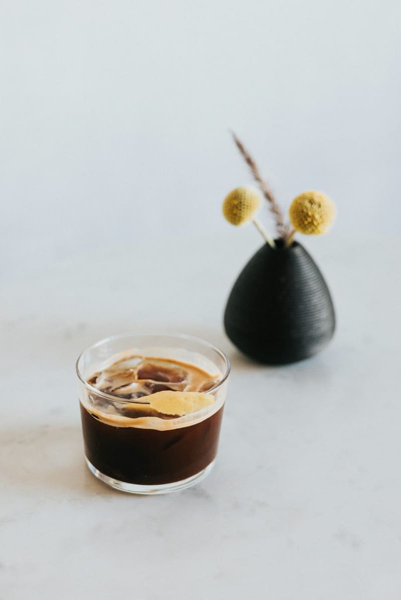 an iced coffee beside a small vase