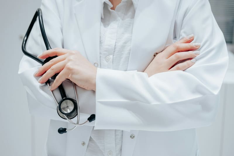 a doctor in a white coat with arms folded