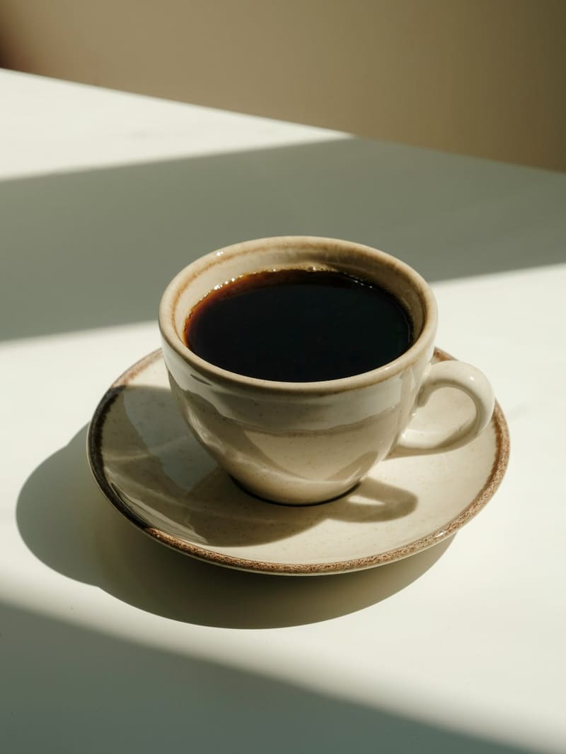 a cup of black coffee in sunlight
