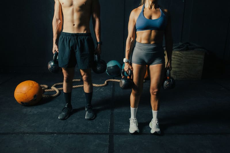 two people holding kettlebells in a gym