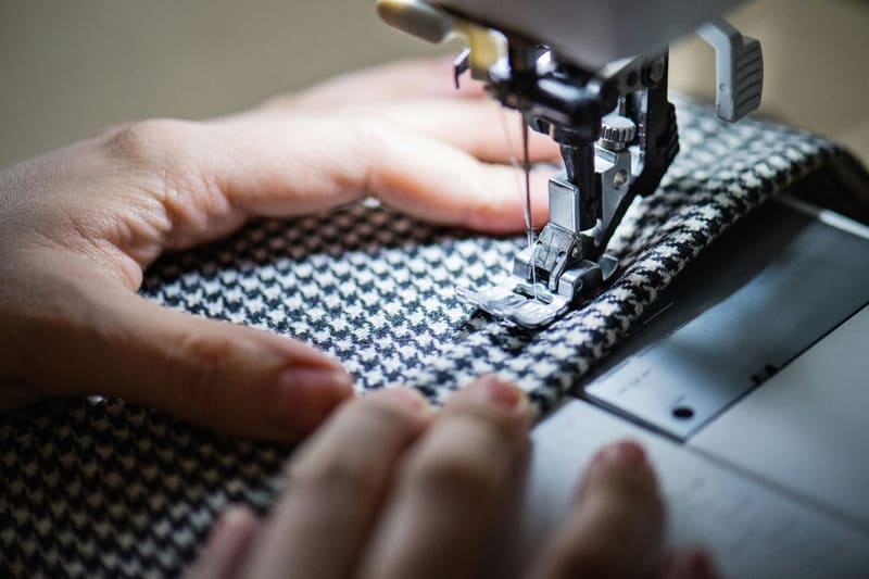 hands feeding tweed through a machine