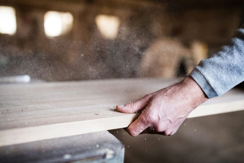 hands sanding a board in dust