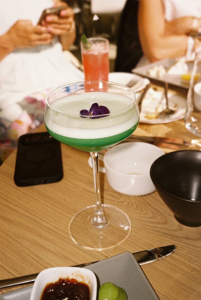 a green cocktail with an edible flower