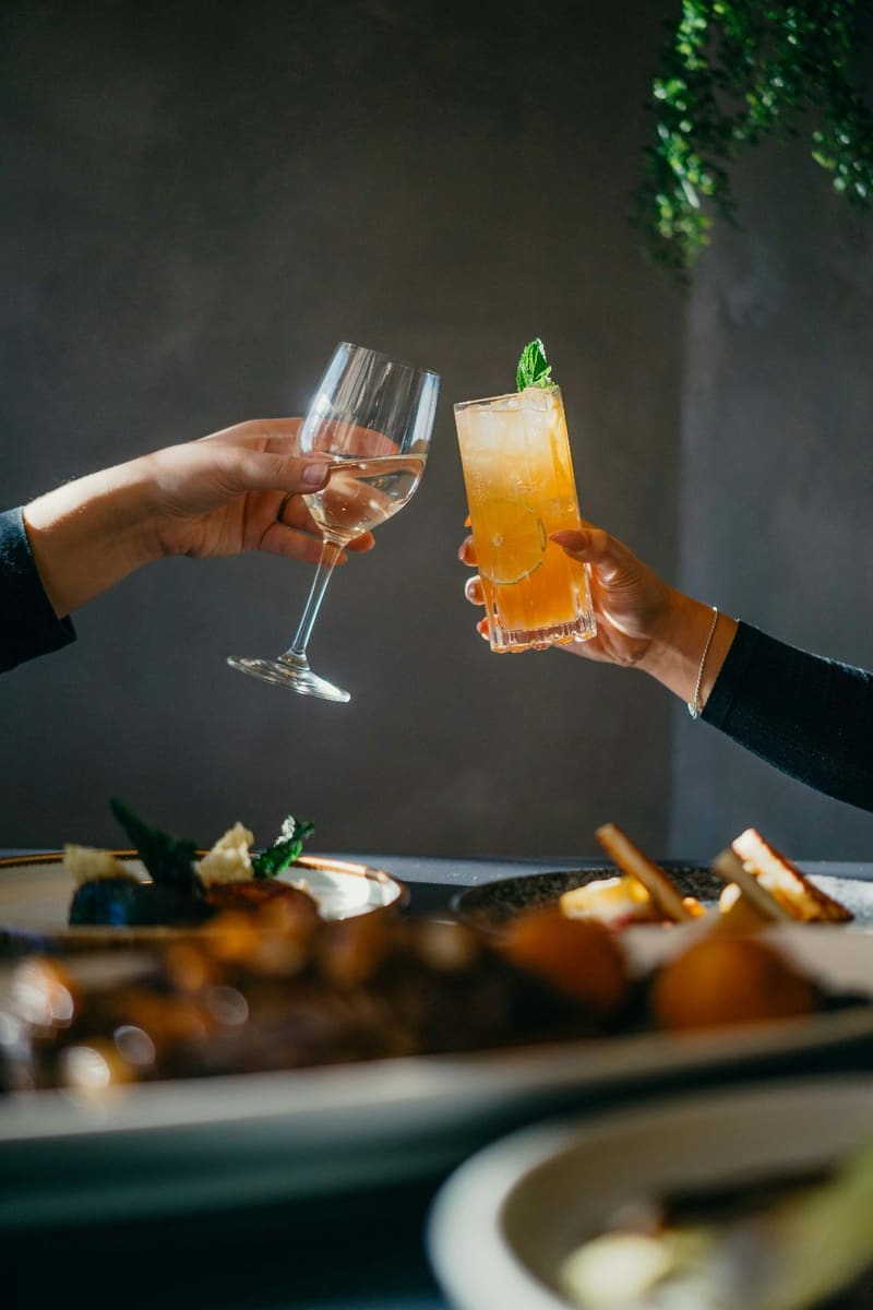 two hands toasting with cocktails