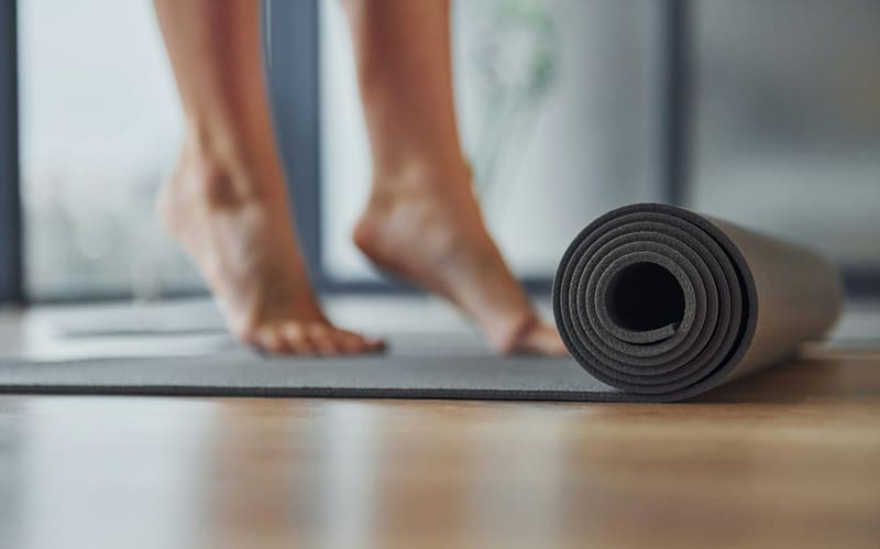 bare feet beside a rolled mat