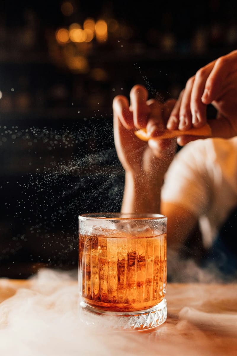 a hand twisting peel over a drink