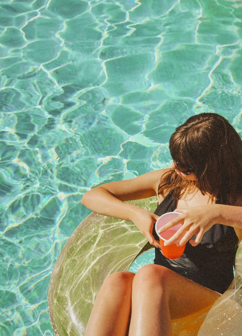 a woman by a pool with a drink