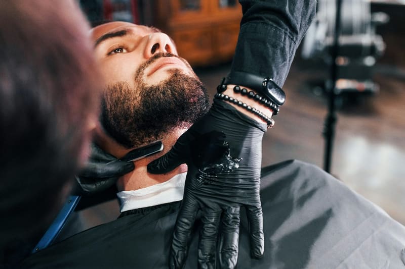a barber shaving a client with a razor