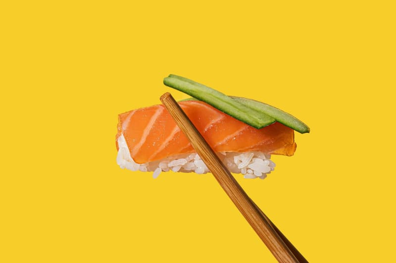 salmon nigiri and cucumber on yellow