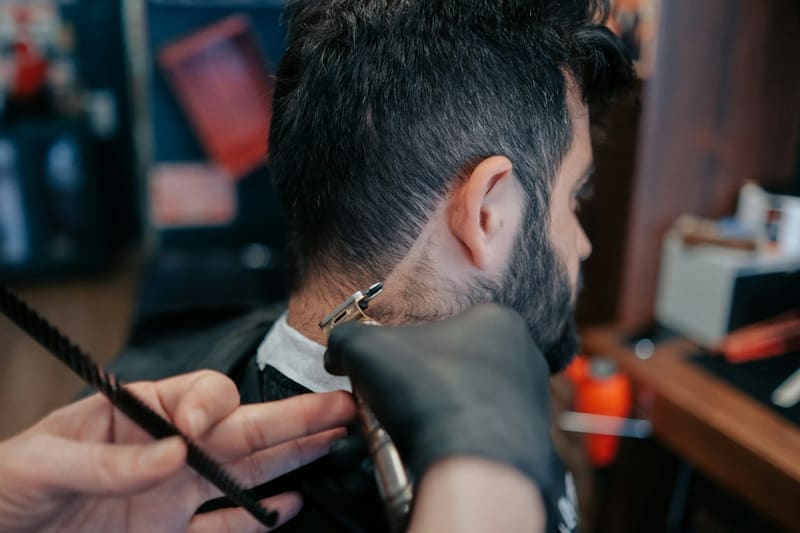a barber trimming a beard with clippers