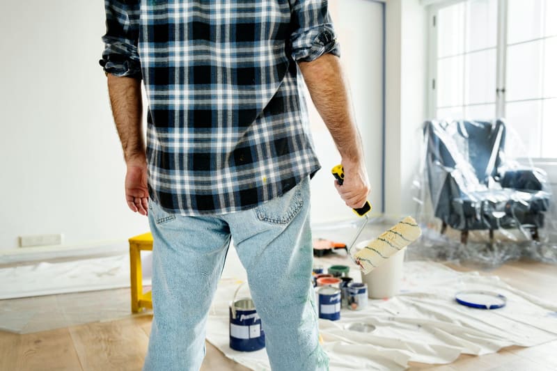 a decorator standing by paint tins