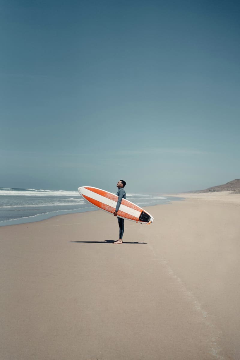 a surfer walking on an empty beach