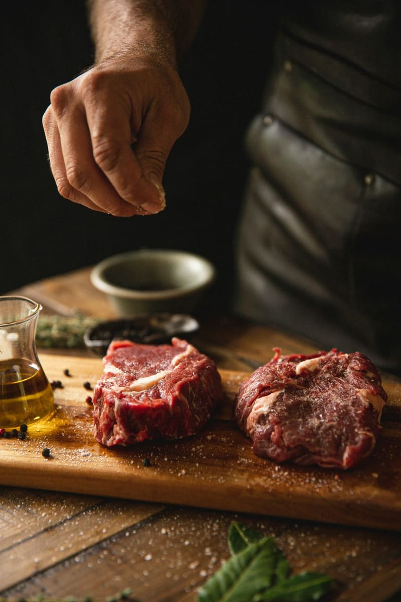 a chef seasoning raw steaks