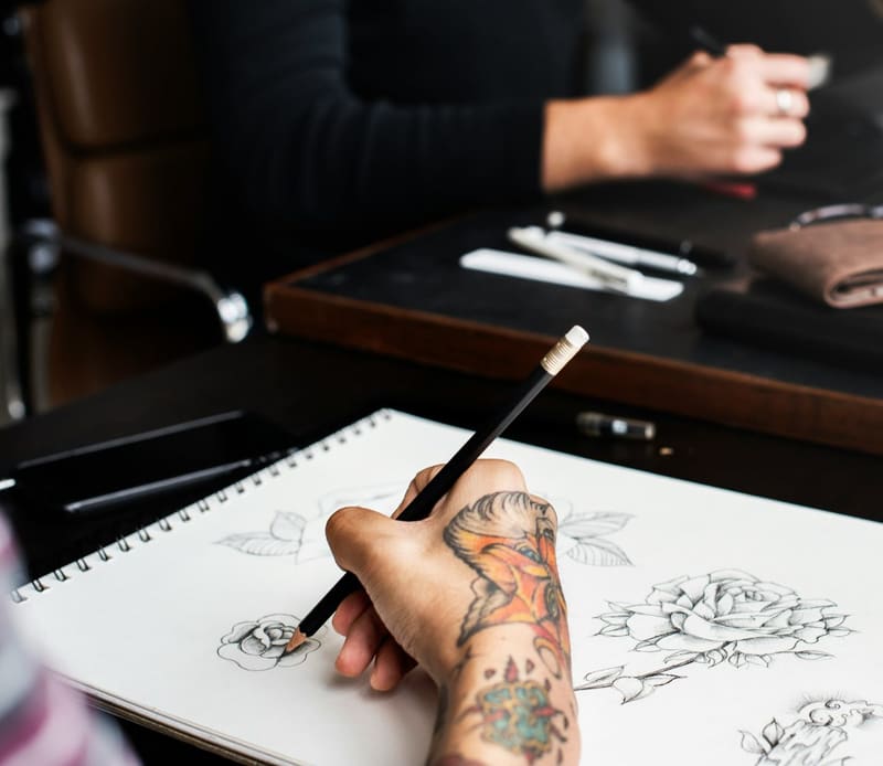 a tattooed hand drawing roses
