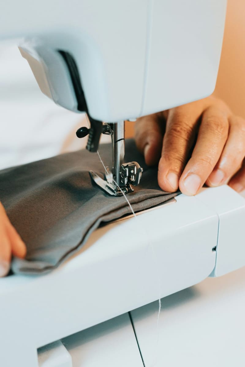 hands sewing grey fabric