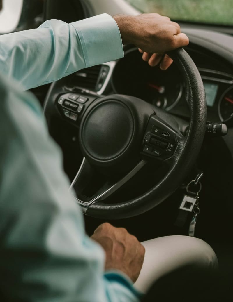 a hand on a steering wheel with keys