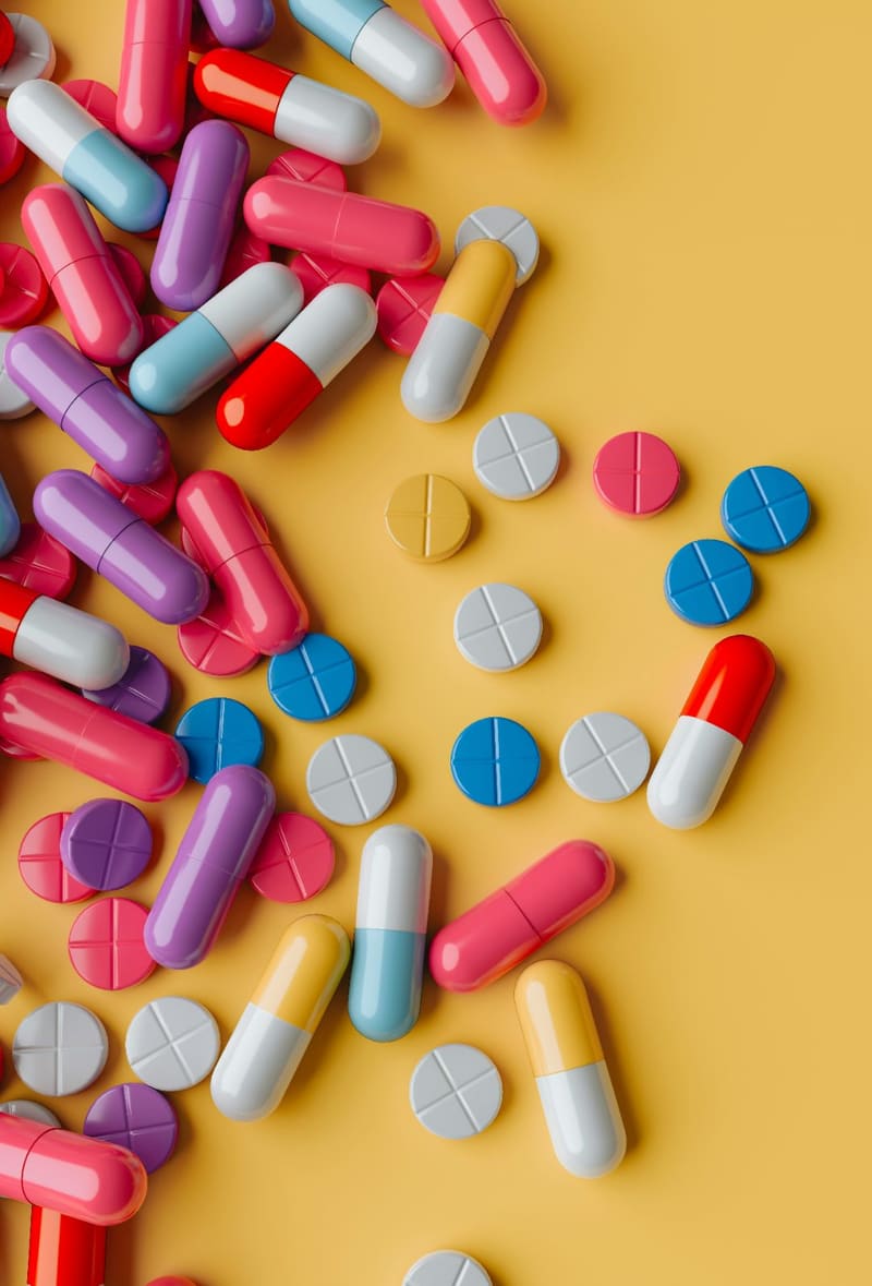 scattered pills and capsules on yellow
