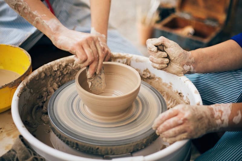two pairs of hands throwing a pot