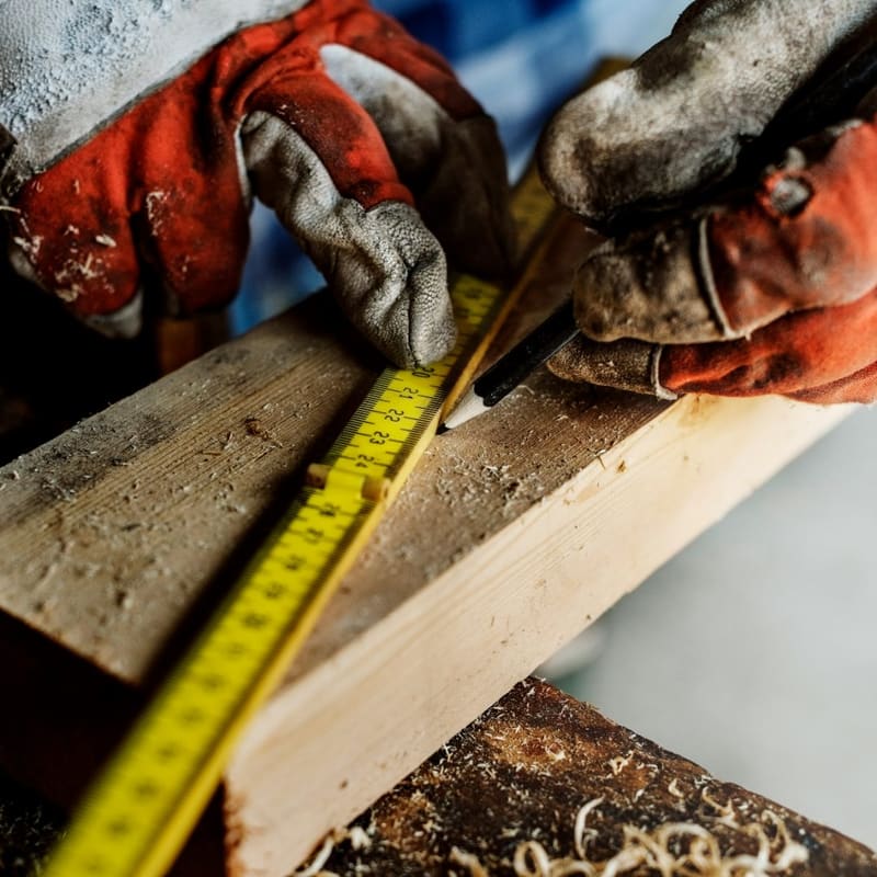 gloved hands measuring a plank