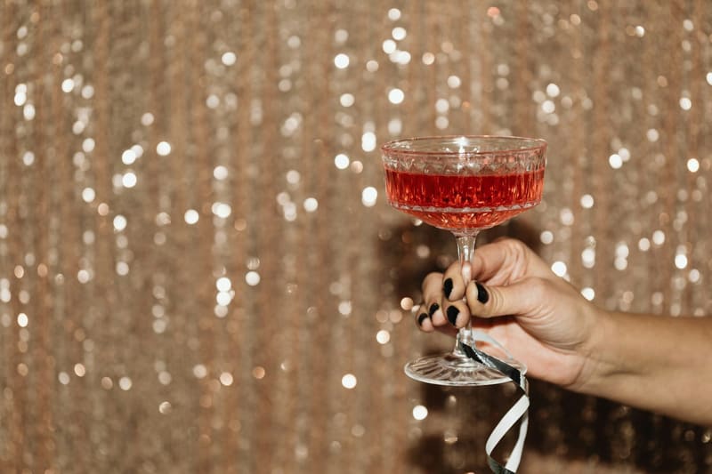 a hand raising a pink cocktail