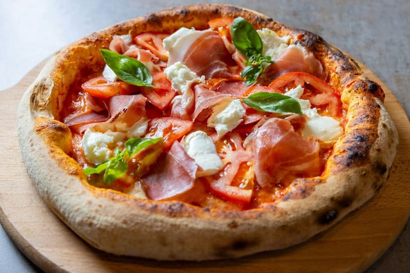 a pizza with prosciutto and burrata