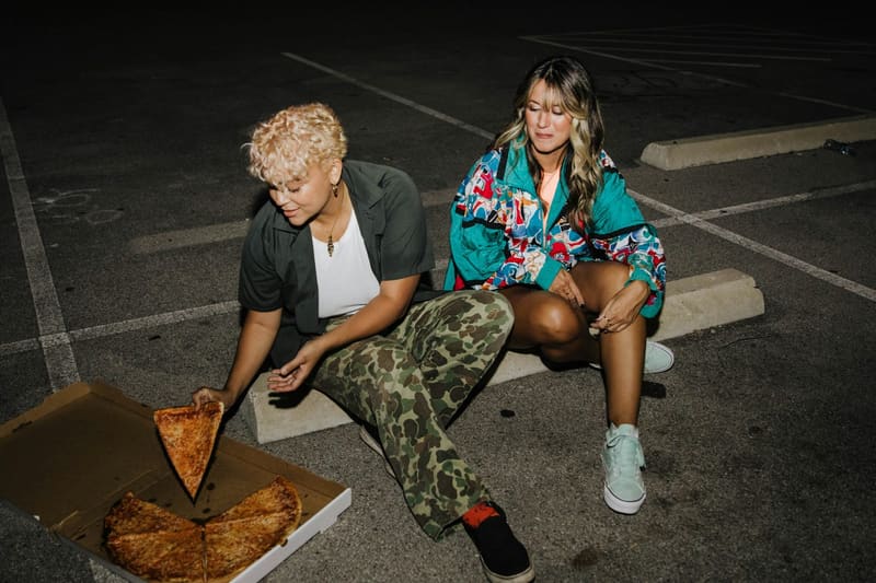 two friends with a pizza box on tarmac