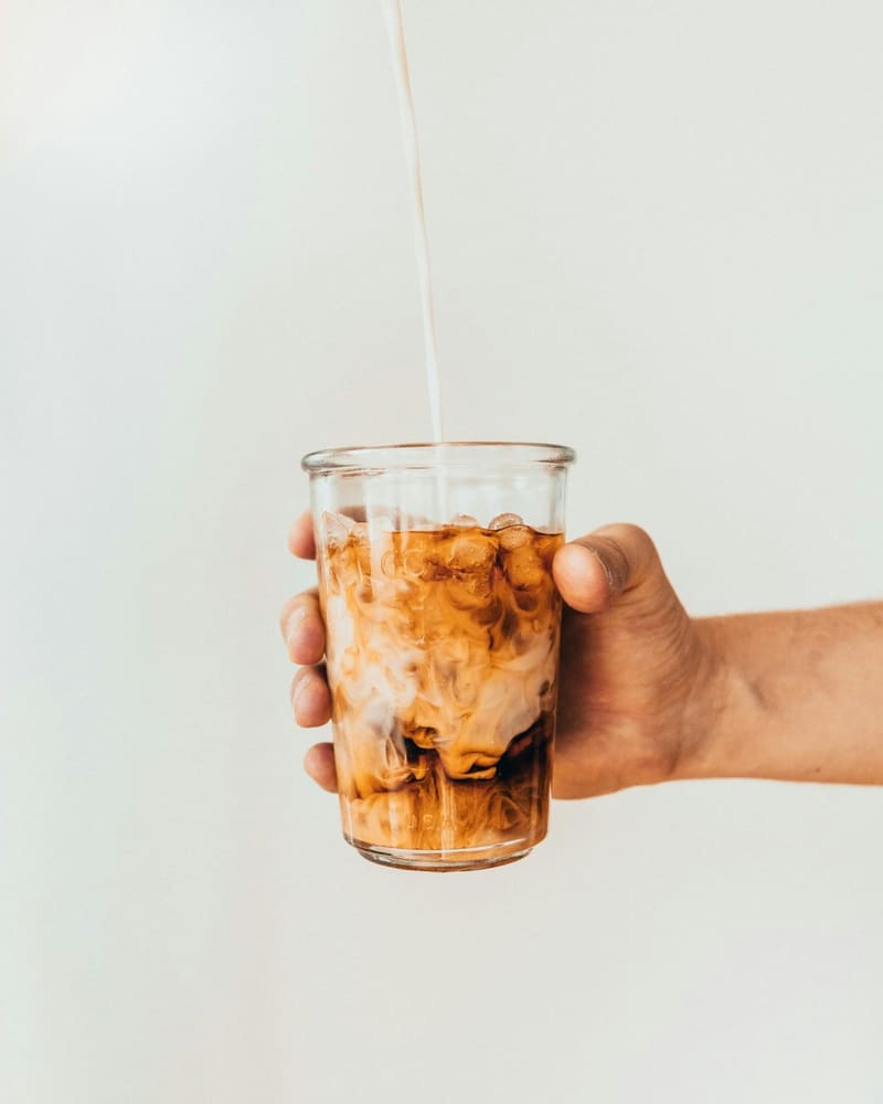 milk poured into an iced coffee glass