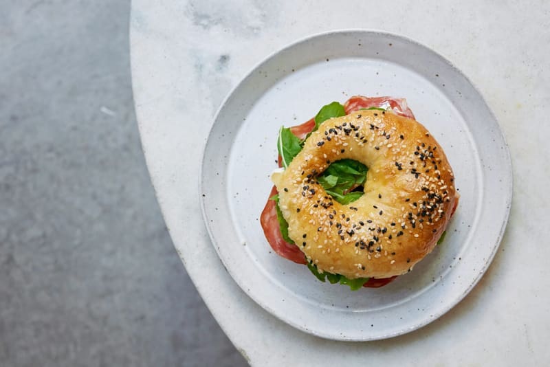 a seeded bagel with tomato and basil